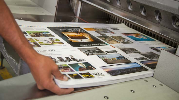 Hands feeding paper into a large-format printer